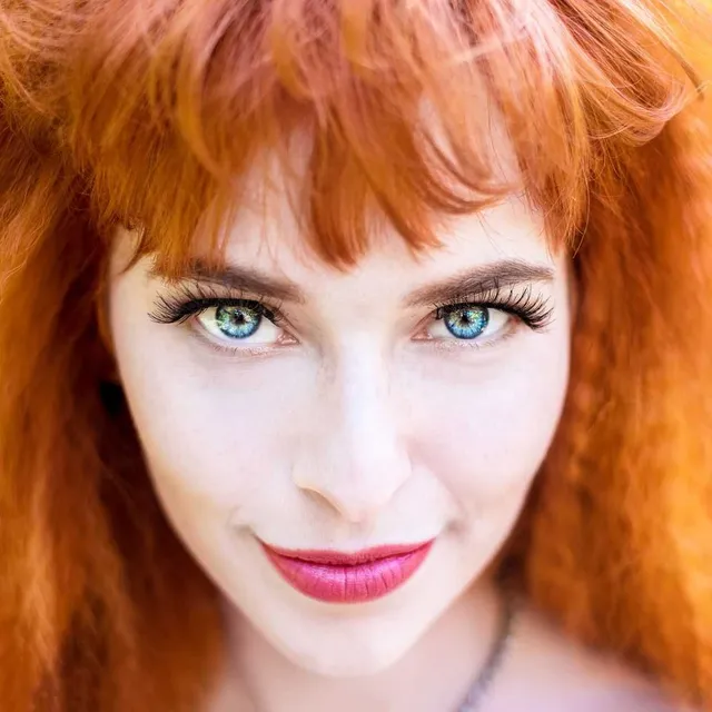 cover galerie Femme rousse aux longs cheveux ondulés, sourire éclatant.