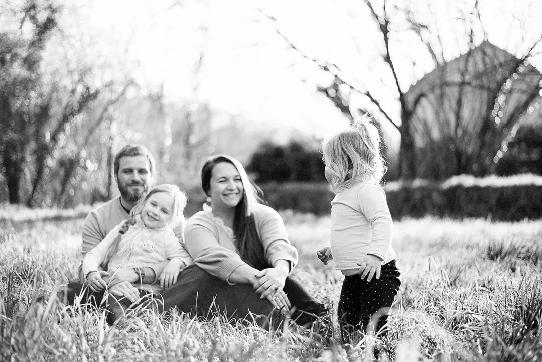 Un couple souriant et sa fille dans un champ de herbe haute.