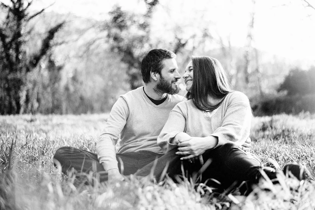 Un couple heureux, assis dans un champ de blé, se blottissent l'un contre l'autre, partageant un moment de tendresse et de bonheur.