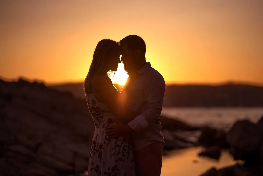 Couple au coucher du soleil sur une côte rocheuse