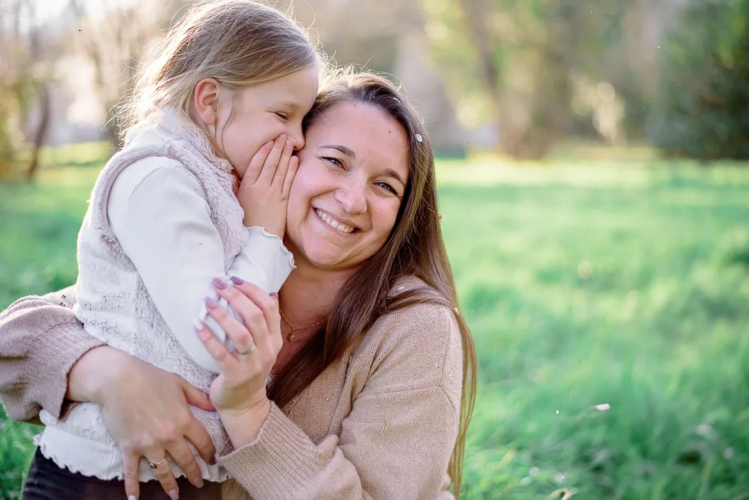 Une maman câline sa fille dans un champ verdoyant au printemps.