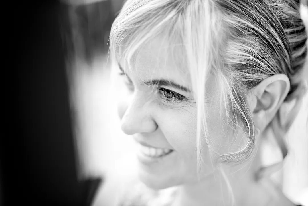 Femme souriante, portrait en noir et blanc, regard vers le bas.