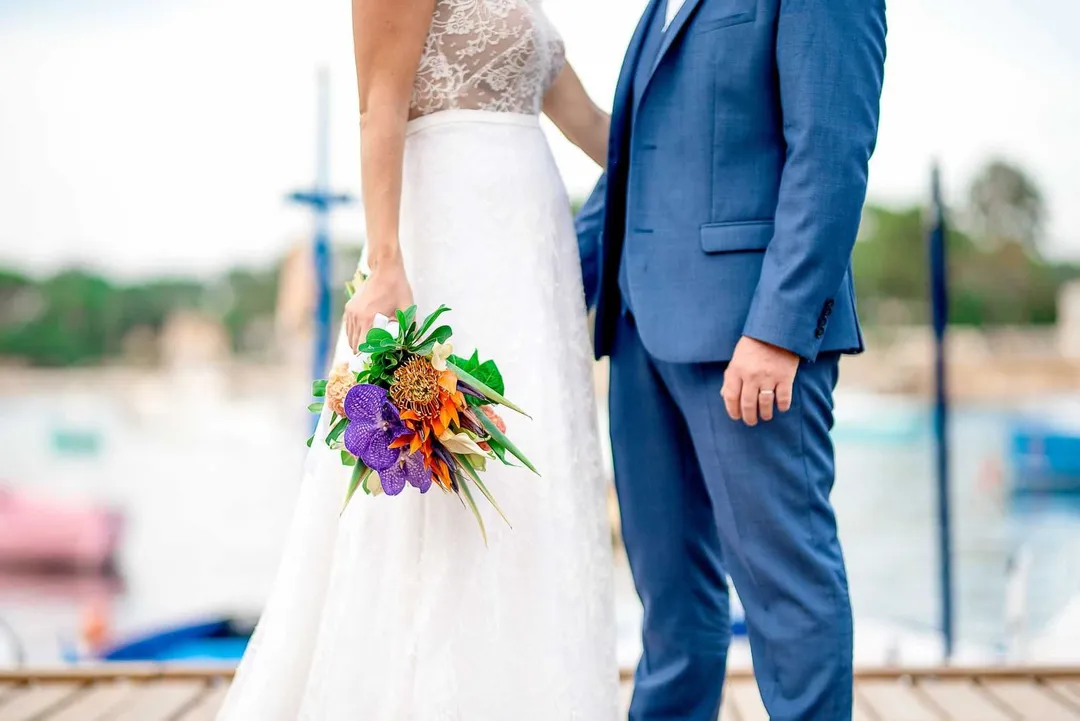 Mariée vêtue d'une robe blanche délicate tenant un bouquet de fleurs exotiques colorées.