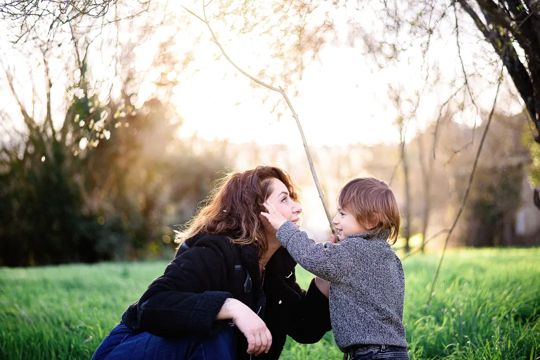 Une mère parle doucement à son fils dans un champ verdoyant au soleil couchant.