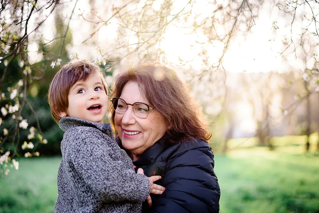 Une grand-mère embrasse son petit-fils dans un jardin fleuri au printemps.