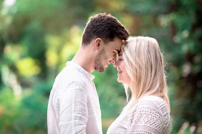 Un couple s'embrasse tendrement dans un écrin de verdure.