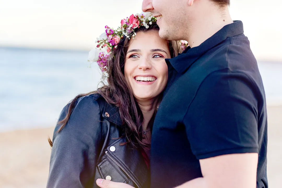 Couple heureux sur la plage, une femme portant une couronne de fleurs et un homme l'embrassant.
