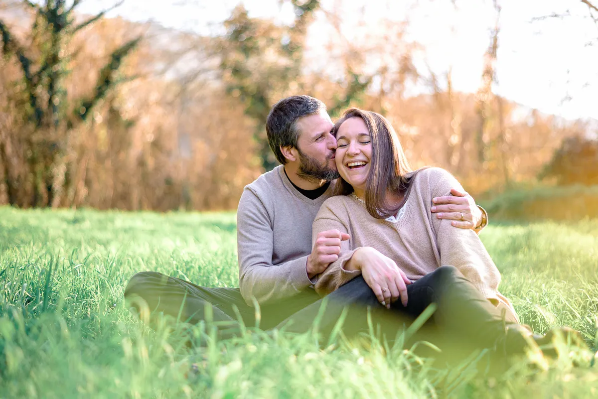 Couple amoureux, assis dans un champ de blé vert, se tenant et souriant.