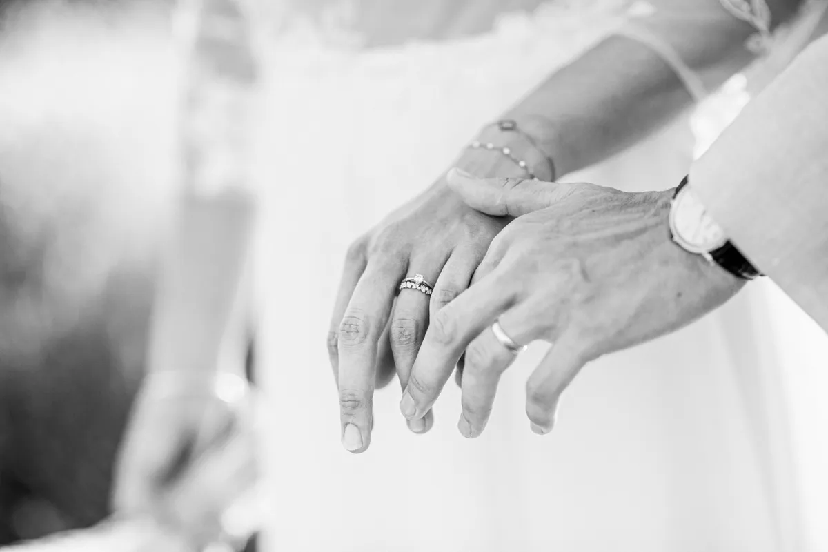 Deux mains se rejoignent, portant des bagues de mariage.