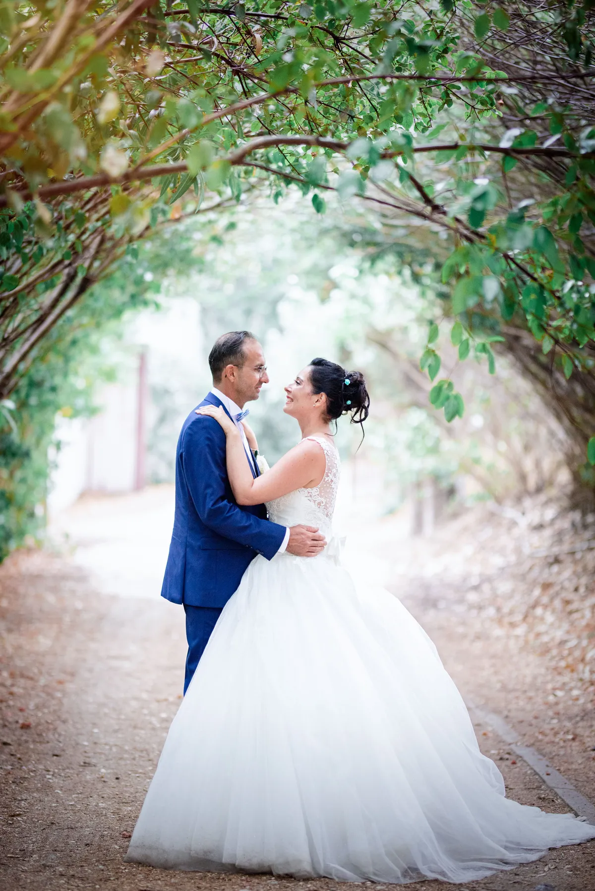 Mariés sous un tunnel de vignes, le couple partage un moment d'intimité et de bonheur.