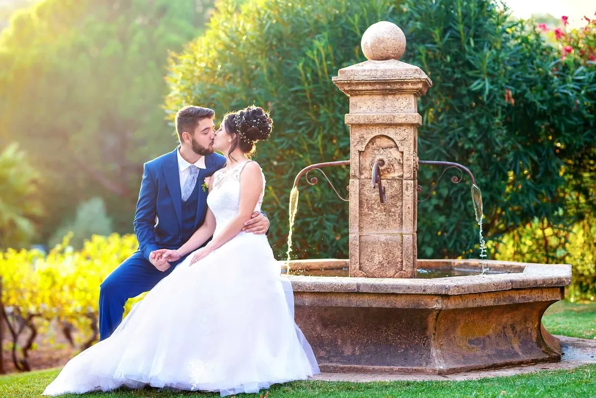 Mariage romantique dans un jardin verdoyant avec une fontaine en pierre.