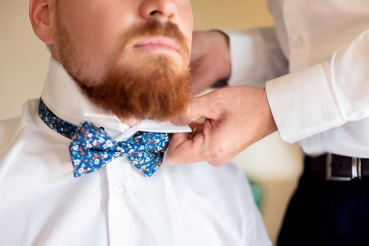 Un photographe ajuste la cravate à motifs floraux de son mari.
