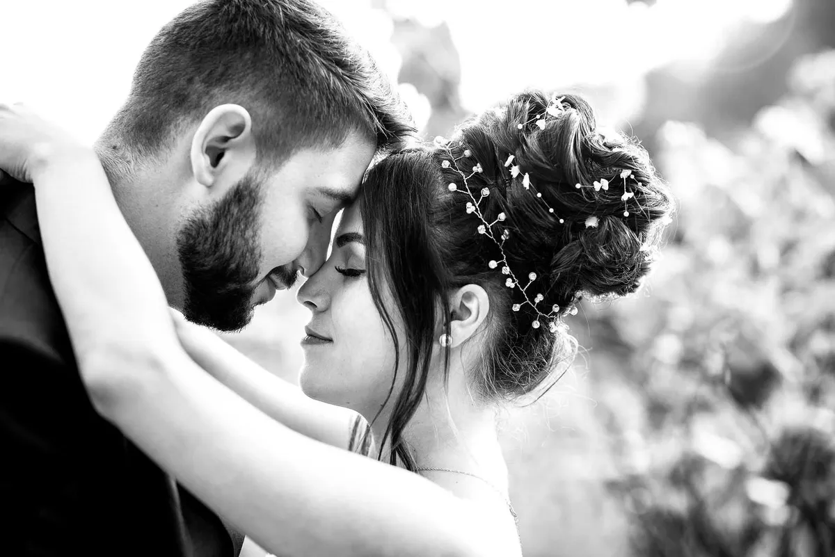 Mariés, le regard perdu dans l'autre, un baiser tendre sous un feuillage luxuriant.