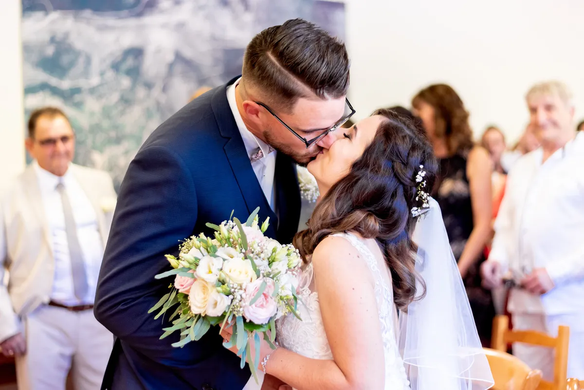 Mariage : Les mariés s'embrassent tendrement sous l'arche florale.