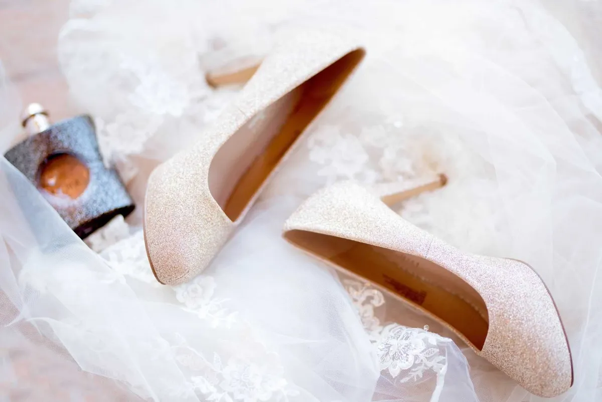 Talons compensés argentés scintillants posés sur un voile de dentelle rose.