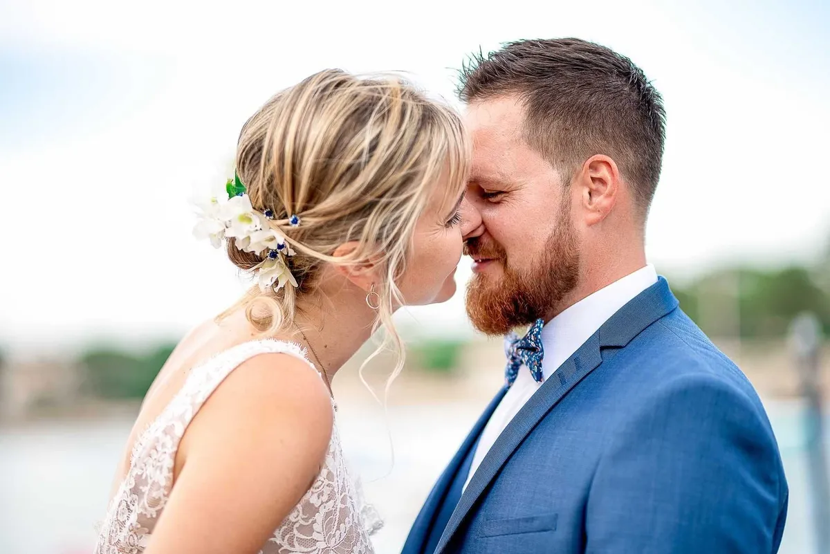 Mariés, le couple échange un baiser passionné sur le rivage.