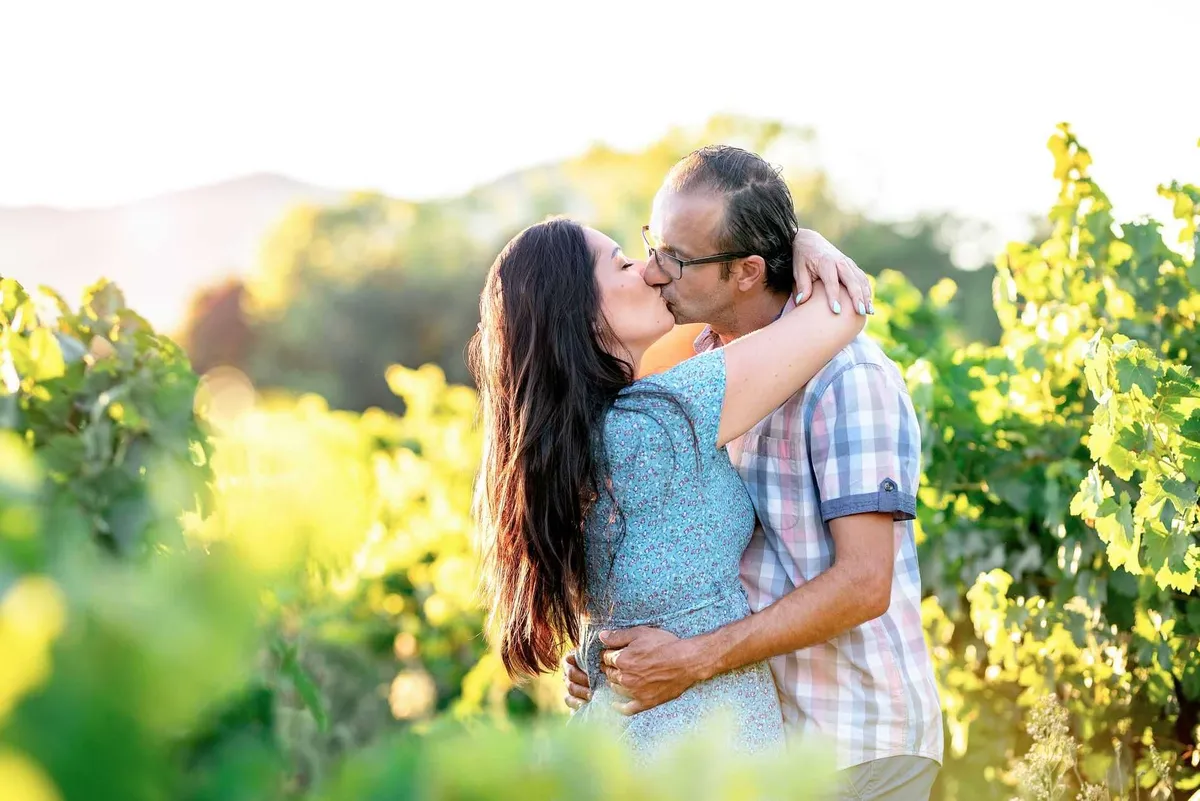 Couple embrassant dans un vignoble baigné de soleil.