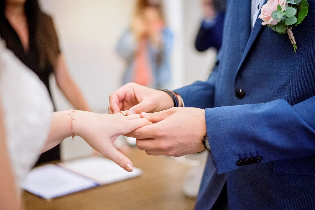 Un mari ajuste délicatement le bague sur le doigt de sa mariée.