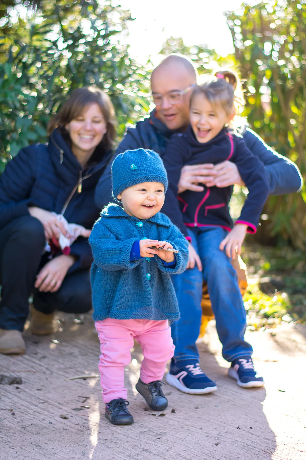 Un bébé s'accroche à une branche d'arbre dans un chemin de terre.