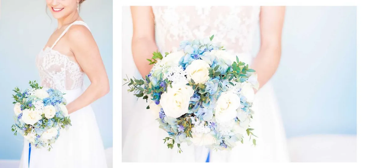 Une mariée vêtue d'une robe en dentelle blanche tient un bouquet de mariée composé de roses blanches, de bleuets et de feuilles de eucalyptus.